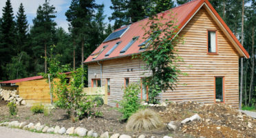 A wooden house with solar panels and a garden providing inspiration and ideas for An Camas Mòr