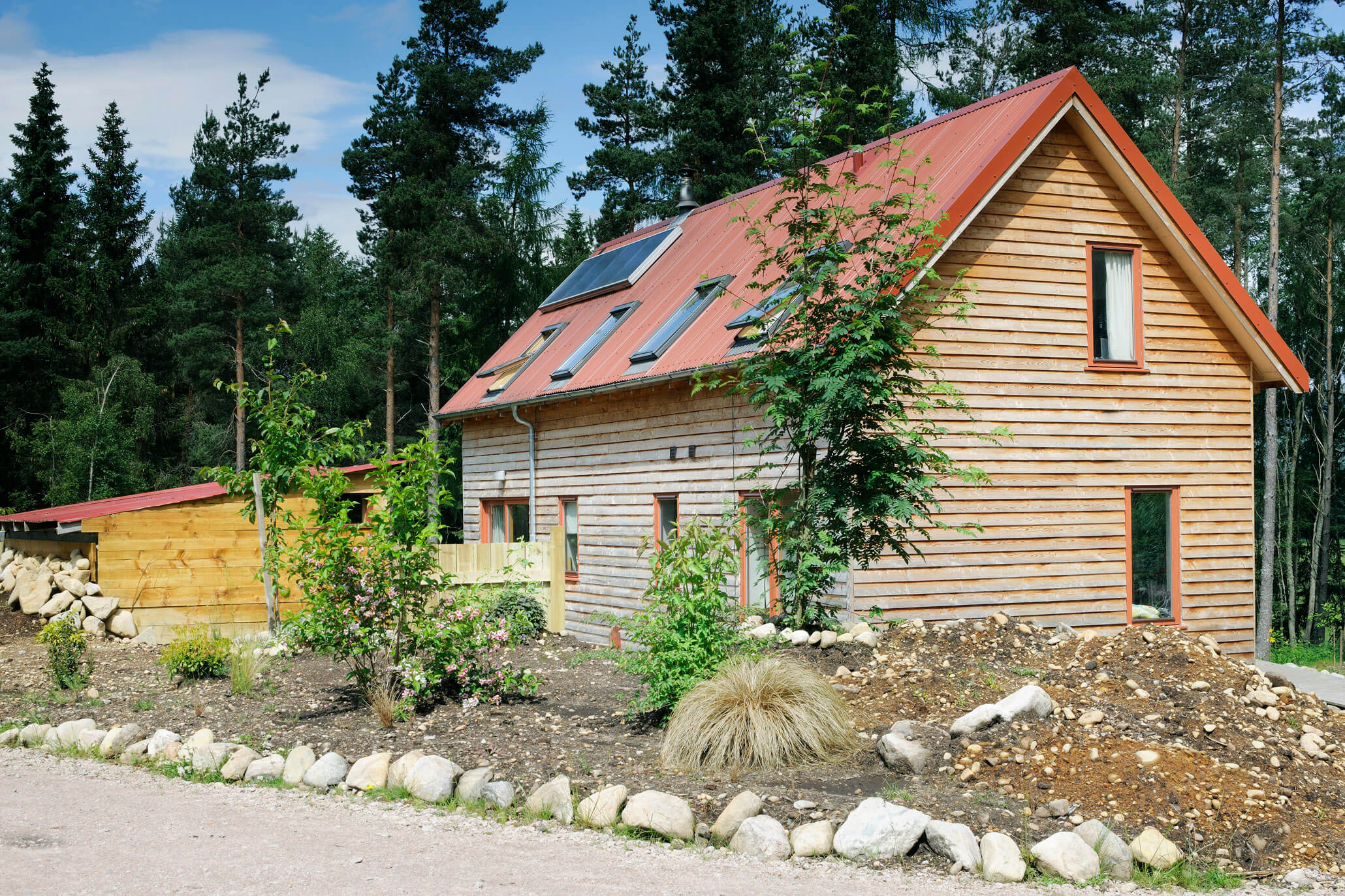 A wooden house with solar panels and a garden providing inspiration and ideas for An Camas Mòr